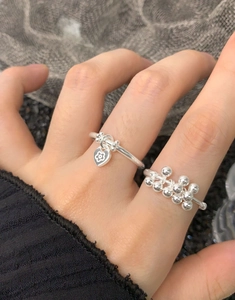 Detail of S925 sterling silver heart charm ring and beaded band set on finger