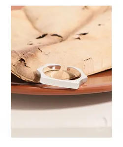 Close-up of geometric S925 sterling silver ring on ceramic plate with soft lighting