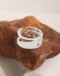 Detailed shot of S925 sterling silver hollow interlocking ring on a natural rock surface