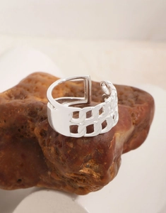 Macro shot of silver hollow chain link ring on dark stone showing fine metal texture