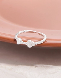Macro detail of S925 silver beaded ring featuring zircon flower and square charms