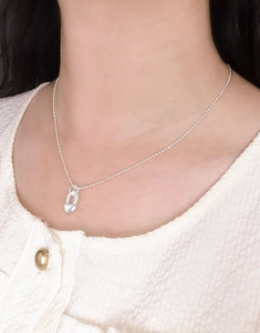 Gros plan d'un collier avec pendentif cadenas cœur en argent S925 sur une chaîne à perles