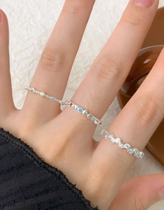 Close-up of stacked S925 silver rings with colorful zircon wave design on finger