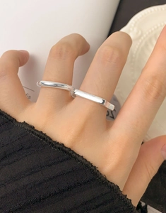 Detailed view of stacked geometric silver rings worn on fingers in a minimalist style