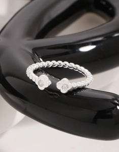 Makroaufnahme S925 Sterlingsilber Perlenring mit Zirkonia-Blumen auf schwarzem Grund