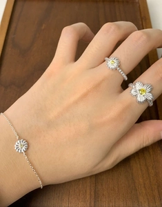 Detail of S925 sterling silver daisy bracelet and rings with yellow cubic zirconia