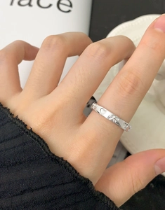 Gros plan d'une bague en argent S925 avec cœur et nœud portée avec une manche noire chic