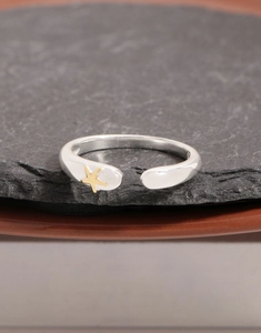 Détail d'une bague ouverte en argent S925 avec étoile de mer dorée sur pierre noire