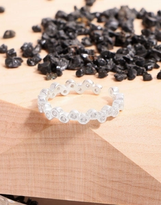 Macro shot of silver sterling ring with multiple round-cut zircons on a wooden stand