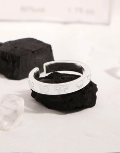 Vue détaillée des motifs en relief cœur et nœud sur une bague argentée ajustable