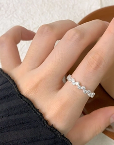 Macro shot of silver wavy eternity ring with sparkling cubic zirconia on model finger