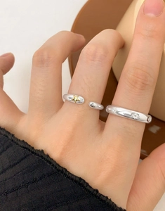 Détail de bagues en argent 925 avec motifs d'étoiles dorées portées par un mannequin