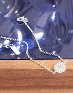 Macro shot of silver daisy charm bracelet with sparkling yellow zircon and lobster clasp