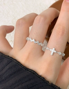 Close-up of S925 silver rings with pavé zircon cross and beaded band on model hand