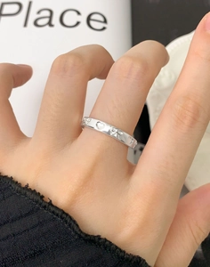 Gros plan d'une bague argentée avec nœud et cœur portée par un mannequin avec un décor chic