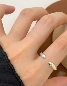 Macro d'une bague ouverte en argent avec une étoile dorée portée au doigt d'un mannequin