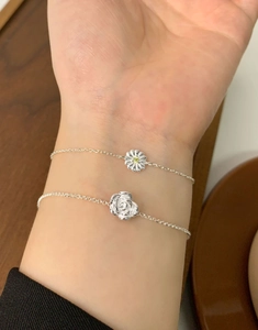 Detail of S925 sterling silver daisy and rose flower bracelets on a wrist