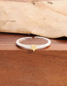 Detail view of S925 sterling silver open ring with tiny golden star on wood
