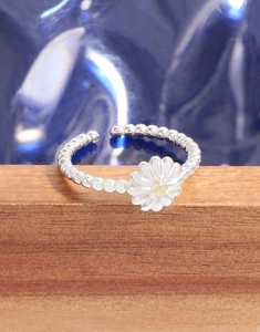 Detailed view of S925 sterling silver daisy ring with yellow gemstone on wood base