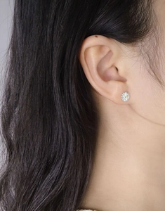 Detailed close-up of a silver daisy stud earring with yellow zircon center on an ear