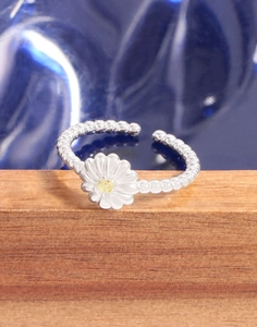 Macro shot of silver daisy ring with yellow gemstone and beaded band on wood