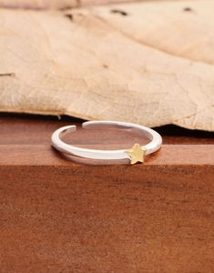 Macro shot of silver ring with gold star detail on a natural wooden background