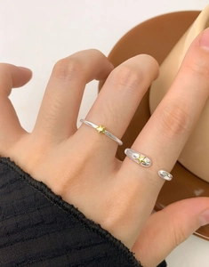 Détail de bagues en argent S925 avec étoiles dorées portées près d'une tasse de café