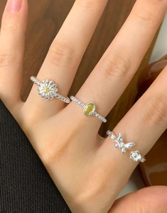 Detailed view of silver daisy and butterfly rings with colorful gemstones on a hand