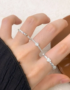 Close-up of rainbow zircon heart rings and beaded bands stacked on fingers