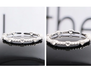 Macro detail of S925 sterling silver ring showing hollow heart beads and S925 hallmark