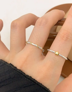 Detail of minimalist S925 silver star ring set with gold wire twist and tiny gold star