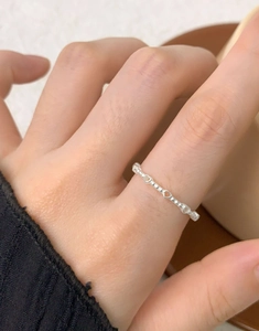 Detail of S925 sterling silver ring with hollow hearts and beads on a model's finger
