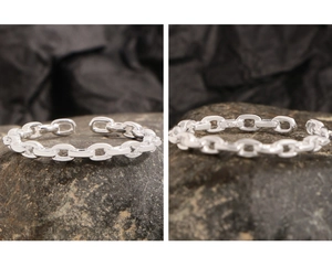 Macro shot of S925 sterling silver minimalist chain ring on dark stone background