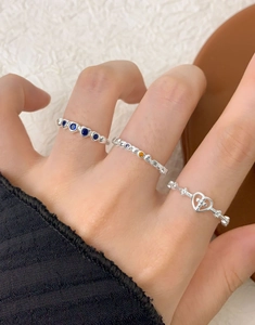 Detailed view of S925 silver rings with blue gems and heart shapes worn on fingers