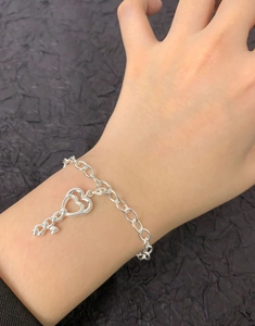 Détail du bracelet en argent S925 à billes avec un pendentif clé en cœur creux au poignet