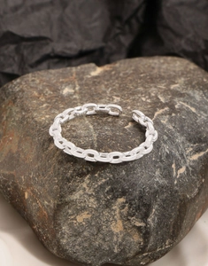 Macro shot of S925 sterling silver chain ring on rock texture with visible S925 hallmark