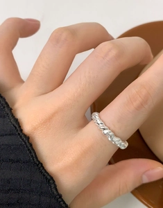 Detail of s925 silver twisted rope ring worn on finger against a coffee cup background