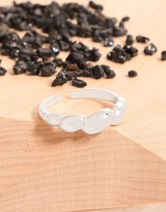 Detail eines S925 Sterlingsilber-Rings mit glatten ovalen Perlen auf Holzsockel