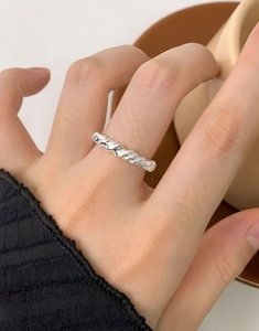 Macro shot of silver twisted rope ring detail with polished spiral texture on a finger
