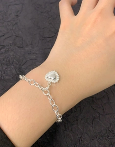 Gros plan d'un bracelet boule en argent sterling S925 avec pendentif cœur pavé au poignet