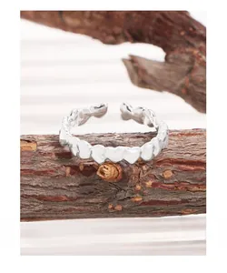 Macro detail of S925 sterling silver ring with embossed heart pattern on wooden stand
