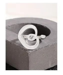 Detail of S925 sterling silver hollow heart ring on a grey stone pedestal
