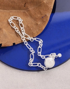 Macro view of silver S925 ball chain bracelet with polished sphere pendant on blue tray