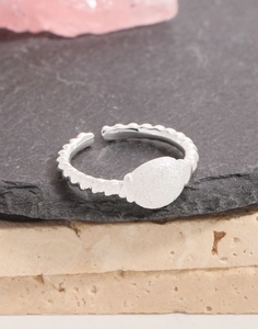 Close-up of a silver twisted rope ring with frosted oval metal plate on stone texture