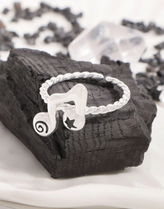 Macro shot of silver musical note ring with black star motif on charcoal and crystal