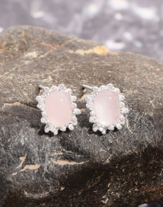 Close-up of pink quartz earrings with vintage silver beaded borders on stone background