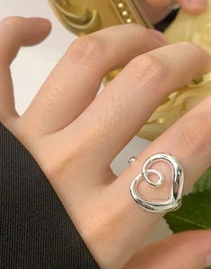 Macro detail of a silver hollow heart-shaped open ring with interior spiral textures