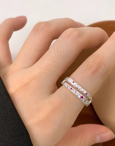 Close-up of a double-layered silver ring with pink and purple zircon stones on a model's finger