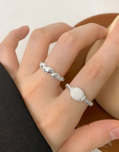 Detail of S925 silver twist rope ring and oval glitter ring set on model's hand