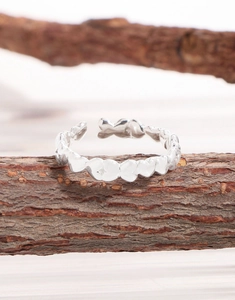 Detail view of continuous heart pattern polished silver ring on natural wood branch